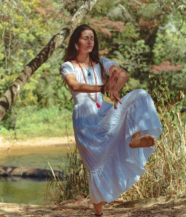 Woman in a dynamic yoga flow pose, surrounded by calm, dark ambiance.